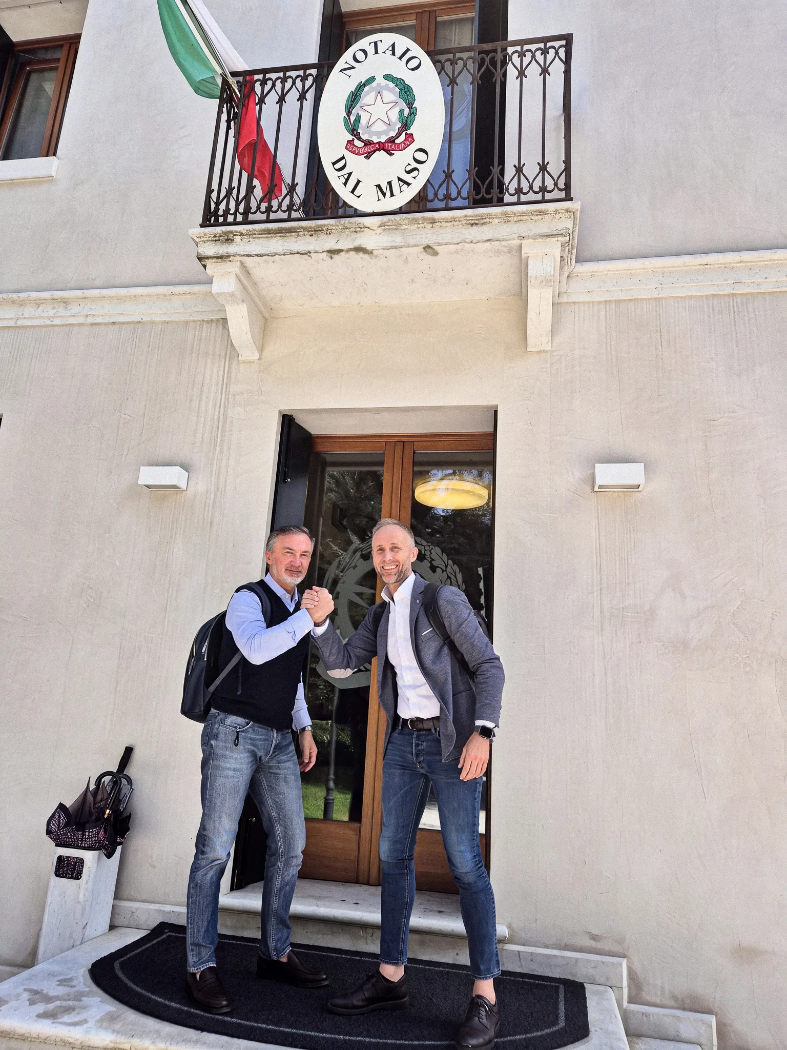 Due rappresentanti di Eleva Coatings si stringono la mano davanti a uno studio notarile