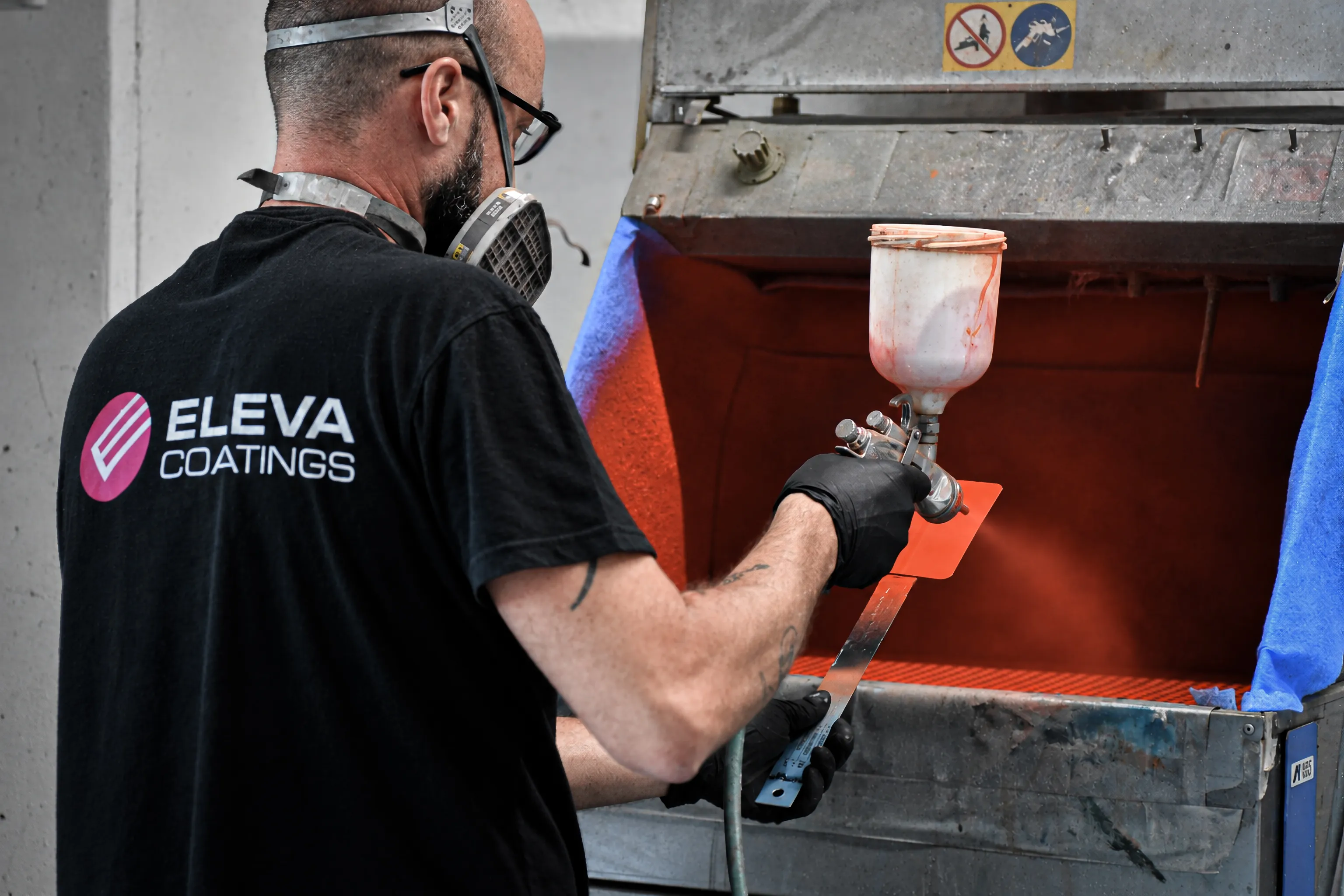 Tecnico Eleva Coatings durante la verniciatura a spruzzo di un campione