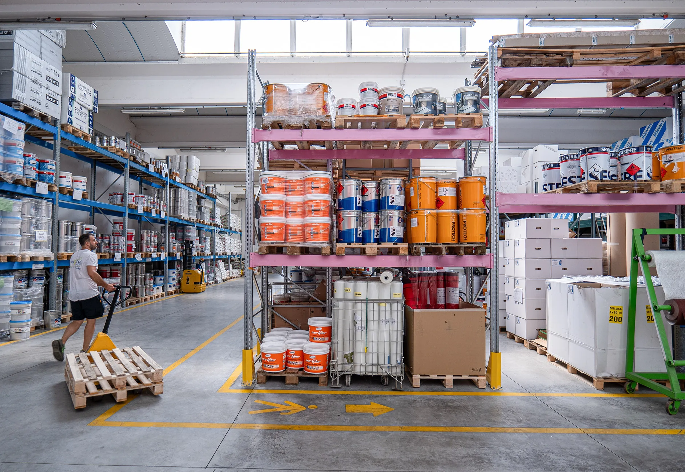 Addetto con transpallet tra le scaffalature del magazzino Eleva Coatings