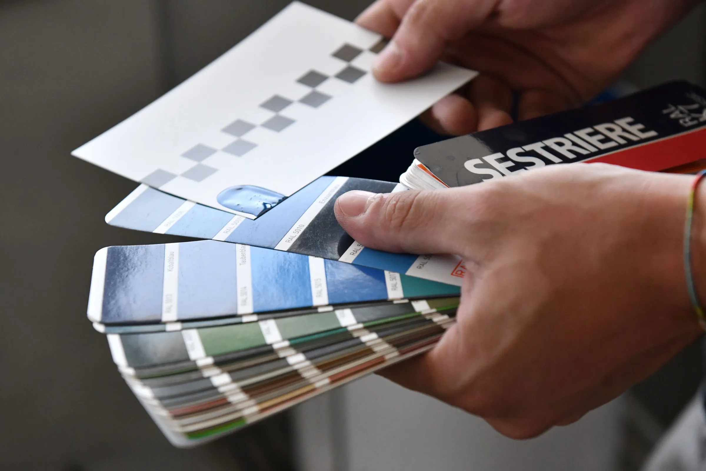 Mani che sfogliano una mazzetta di colori RAL